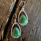 Green stone earrings on a wooden surface