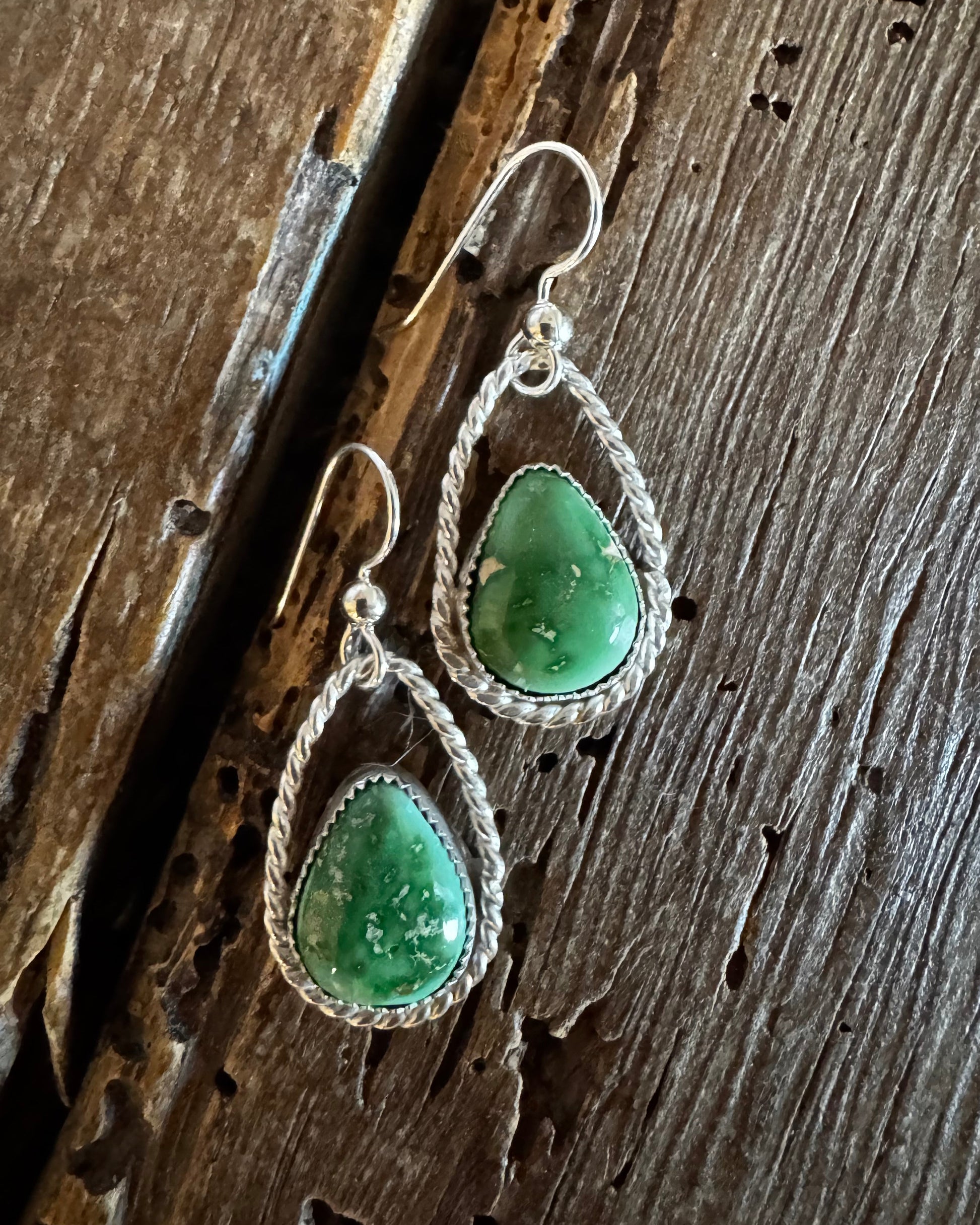 Green stone earrings on a wooden surface
