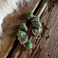 Green gemstone earrings on a wooden surface with fur