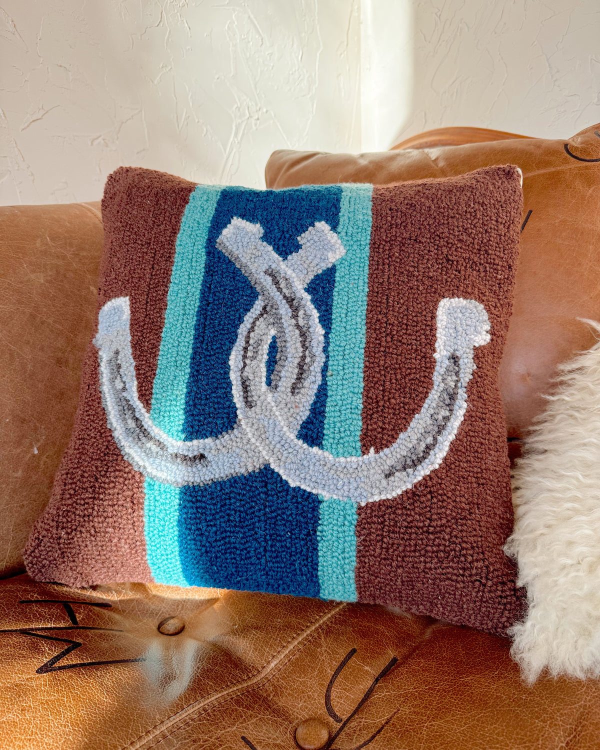 Decorative pillow with horse shoes on a brown couch