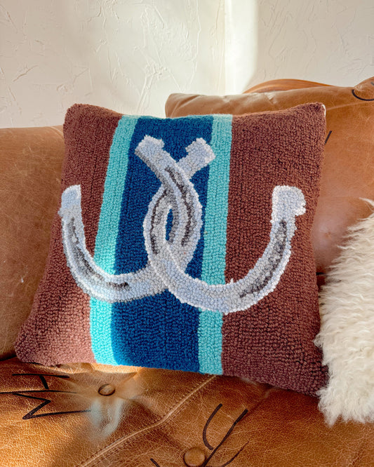 Decorative pillow with horse shoes on a brown couch