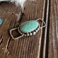 twilly slide with a green stone on a wooden surface
