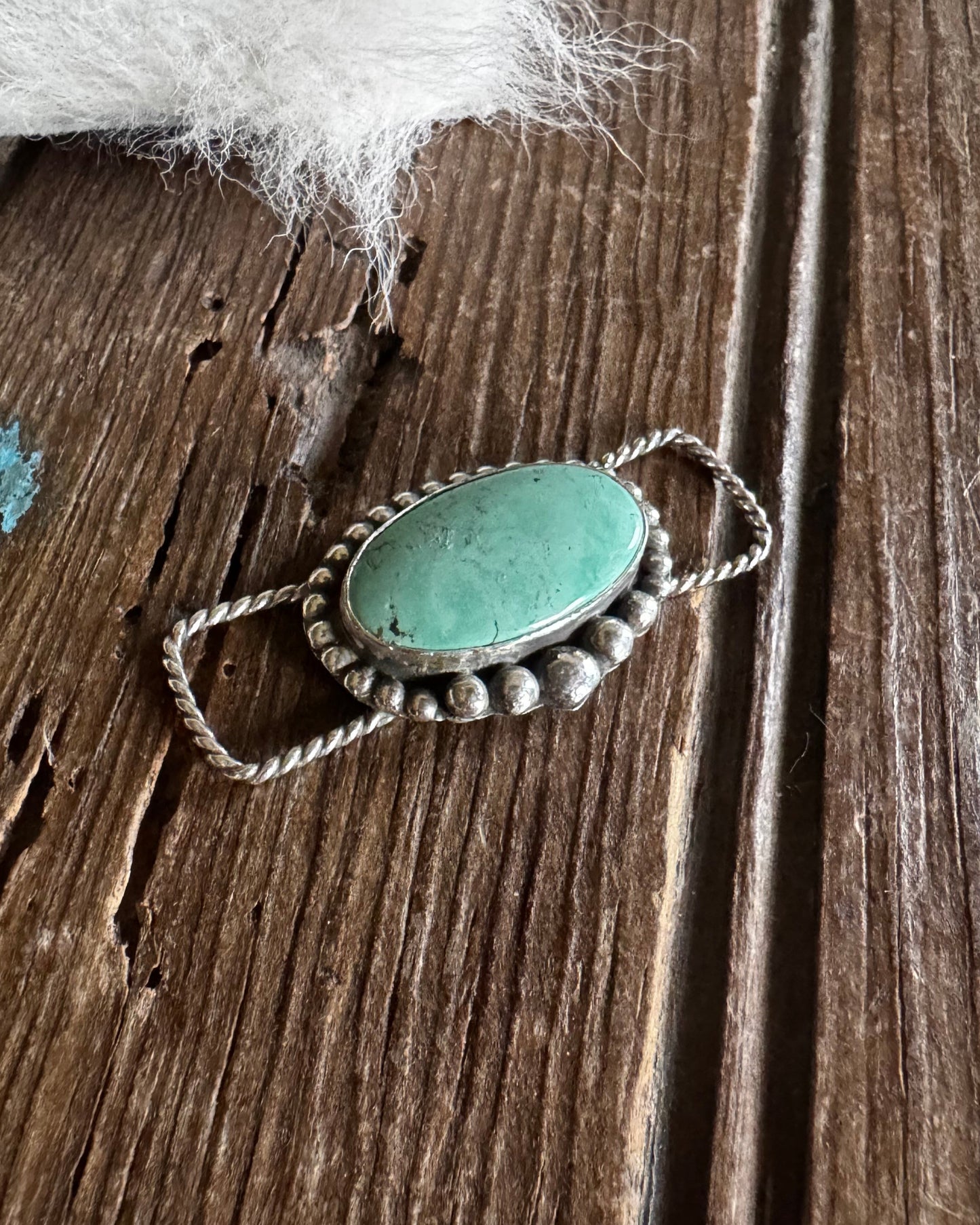 twilly slide with a green stone on a wooden surface
