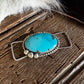 Turquoise stone pendant on a wooden surface with fur in the background
