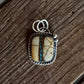 Silver pendant with a stone on a wooden surface
