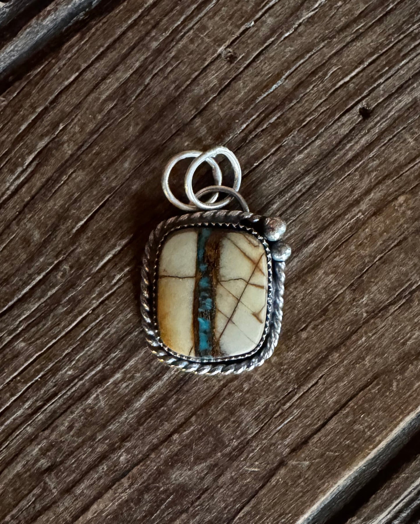 Silver pendant with a stone on a wooden surface