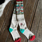 Pair of patterned socks with red, green, and multicolor design on a wooden surface.