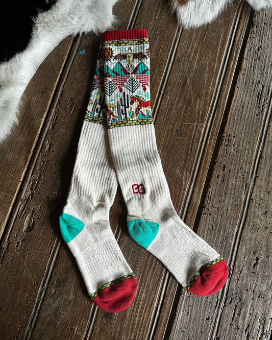Pair of patterned socks with red, green, and multicolor design on a wooden surface.