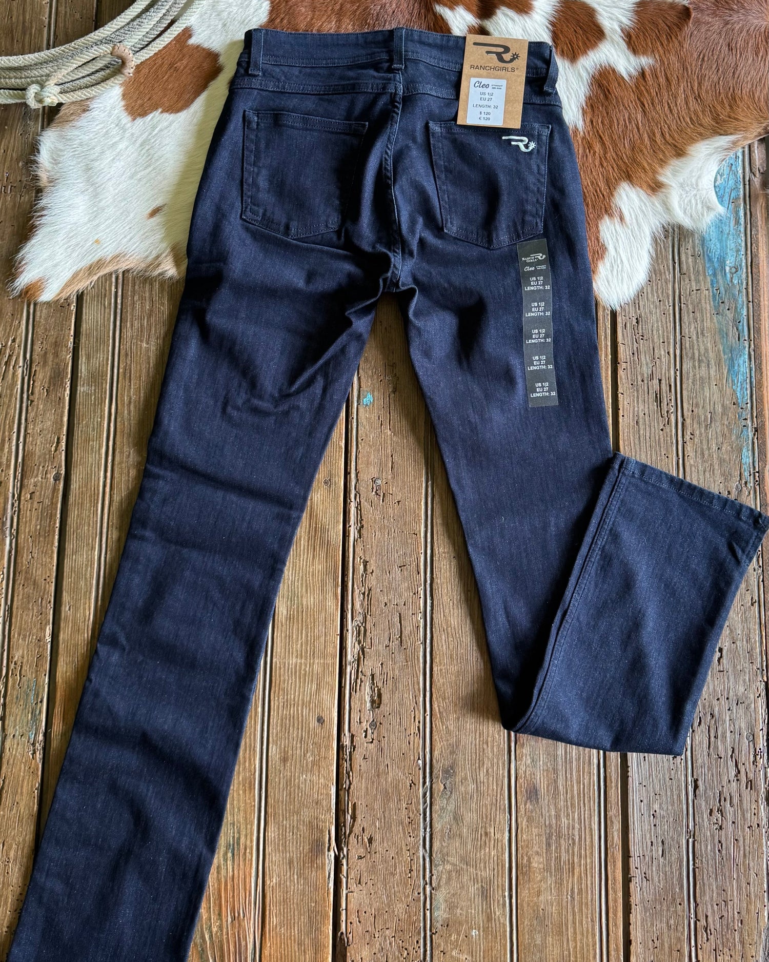 Navy blue jeans with a brand tag on a wooden surface with cowhide rug