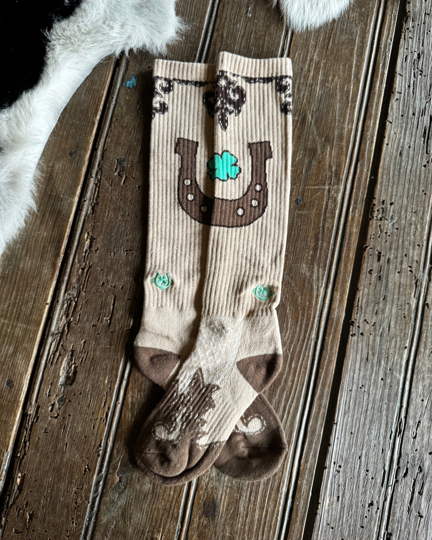 Pair of socks with horseshoe and shamrock design on a wooden surface