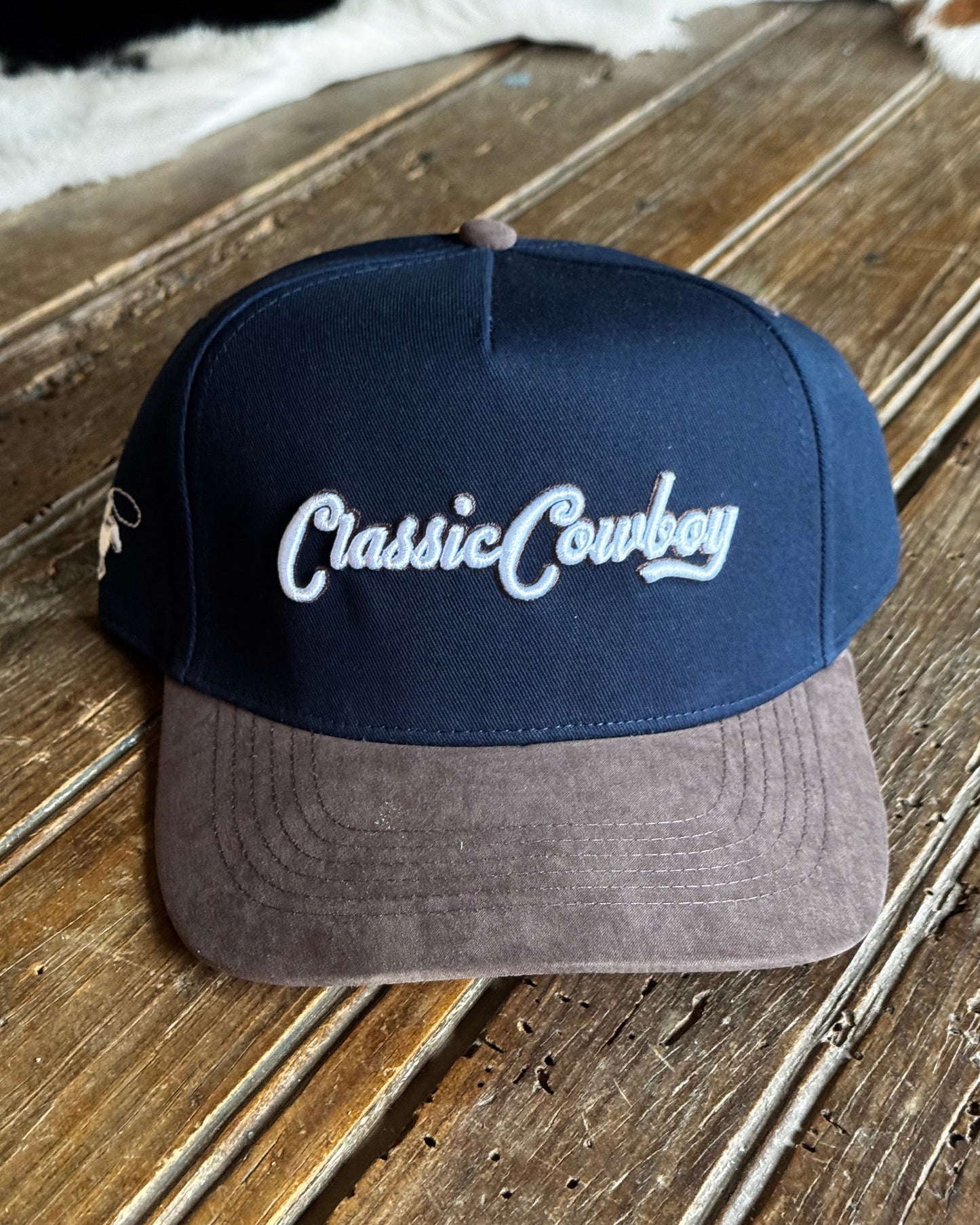 Blue and gray cap with 'Casual Cowboy' text on a wooden surface