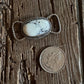 Silver twilly slide and coin on a textured wooden surface