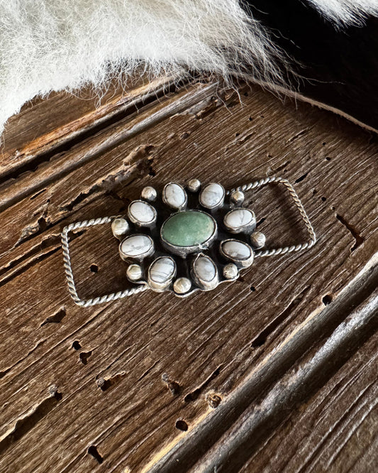Silver twilly slide with a green stone on a wooden surface