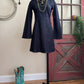 Navy dress on a mannequin with turquoise cowboy boots on a wooden floor.