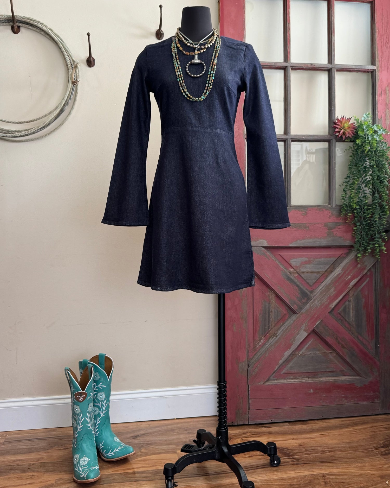 Navy dress on a mannequin with turquoise cowboy boots on a wooden floor.