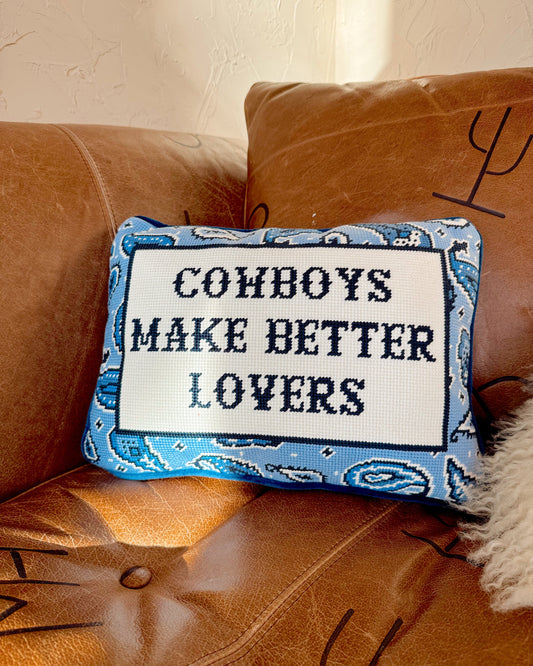 Decorative pillow with 'Cowboys Make Better Lovers' text on a brown couch.