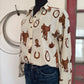 Mannequin wearing a patterned shirt with cowboy designs in a rustic setting.