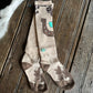 Pair of brown and beige socks with horse shoe design on a wooden surface