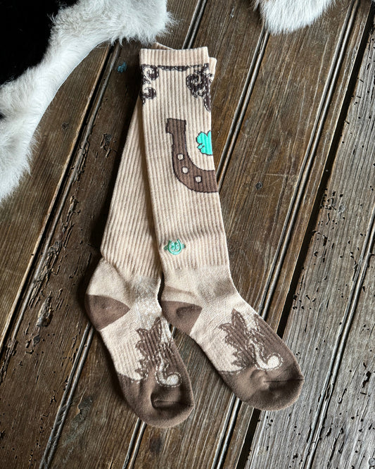 Pair of brown and beige socks with horse shoe design on a wooden surface