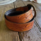 Brown leather belt with intricate designs on a wooden surface