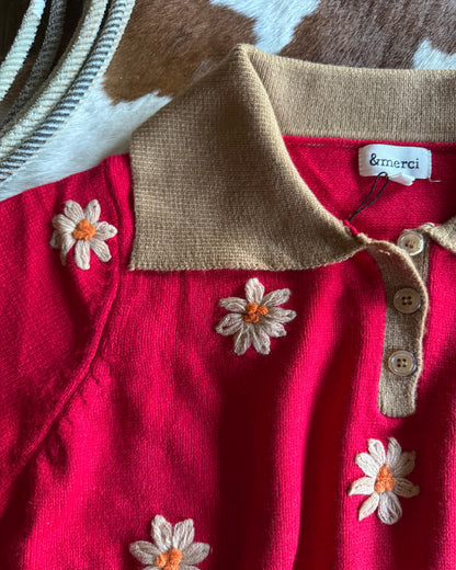 Red garment with beige collar and flower embroidery, featuring the brand 'emergi'.
