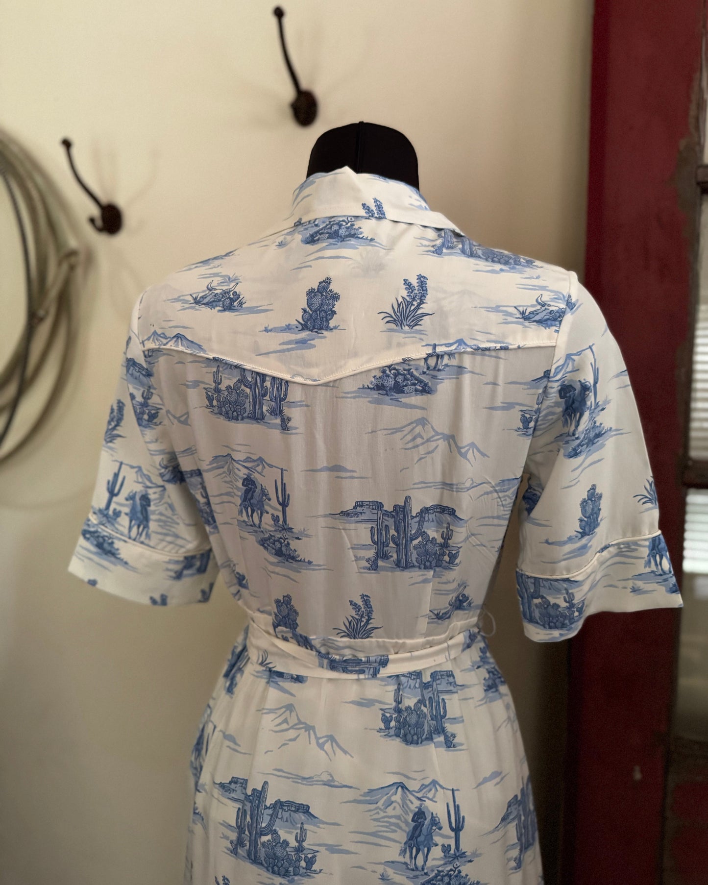 back of blue and white dress in front of a wall and red door