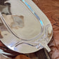 Silver tray on a wooden surface with a leather item underneath