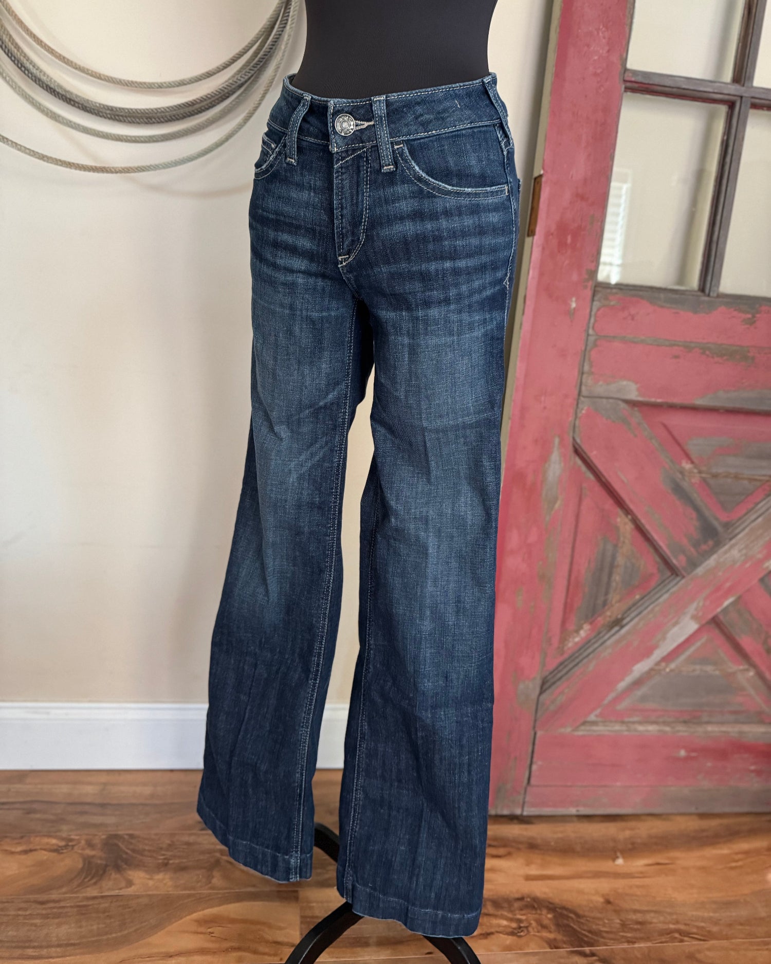 Blue jeans worn by a person standing in front of a decorative wall.