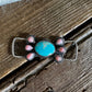 Pink conch and turquoise twilly slide on rustic wooden background 