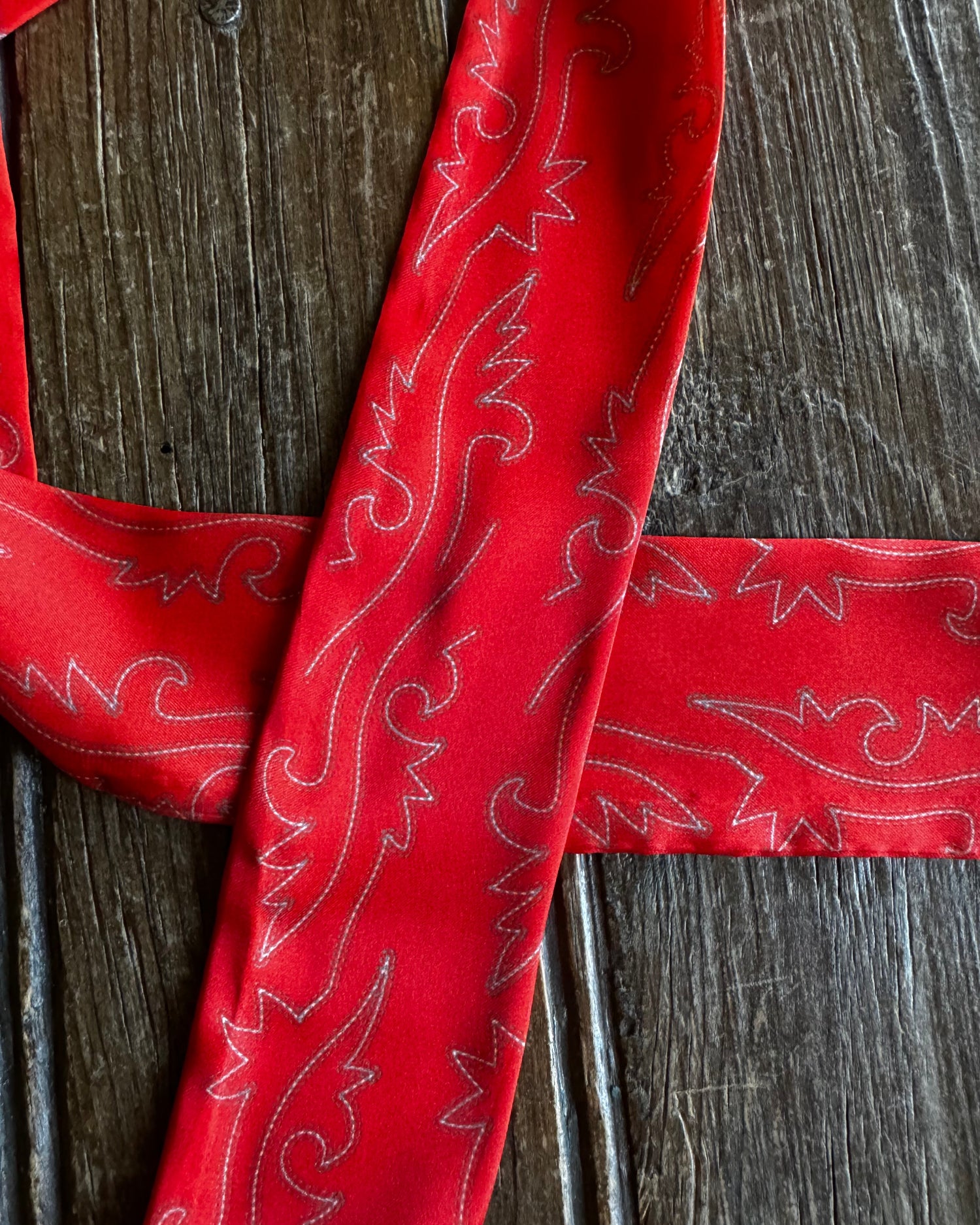 Red fabric with white embroidery on a wooden surface