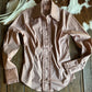 Pink blouse with ruffled details on a wooden surface with cowhide rug in the background