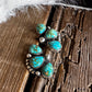 Silver earrings with turquoise stones on a wooden surface