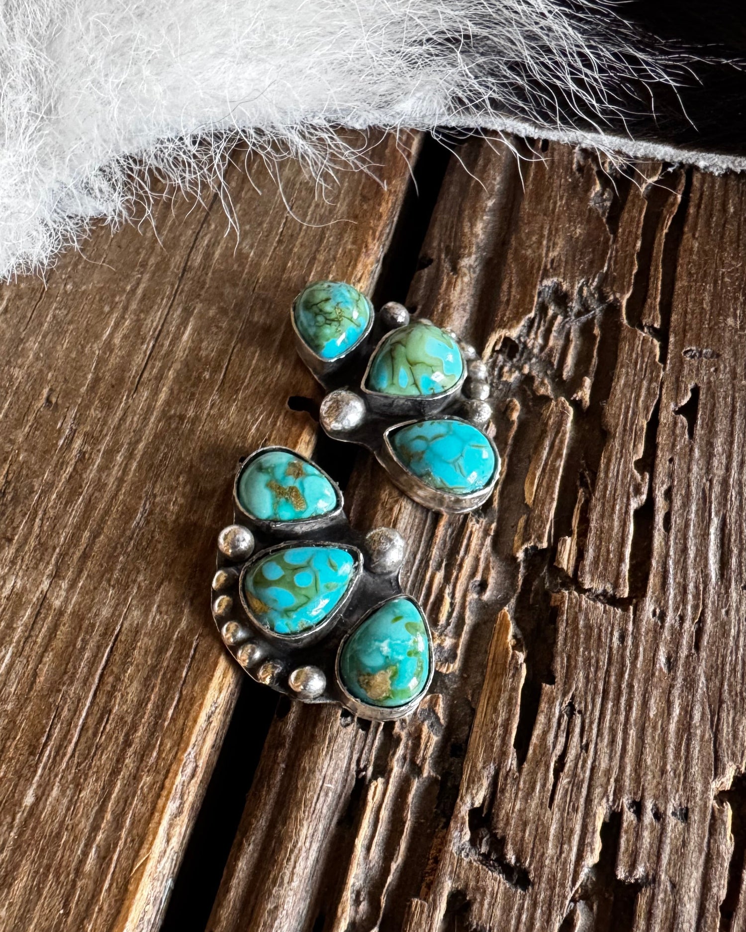 Silver earrings with turquoise stones on a wooden surface