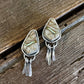 Teardrop-shaped stone earrings on a wooden surface