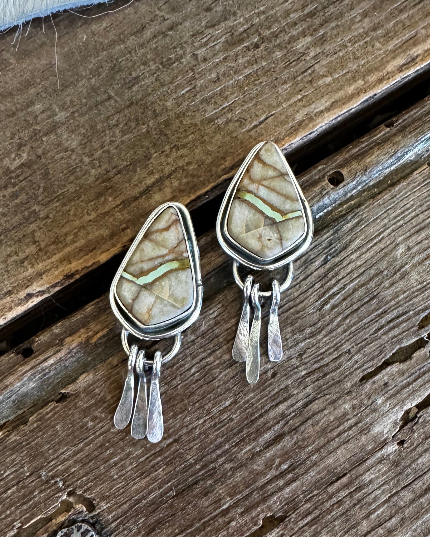 Teardrop-shaped stone earrings on a wooden surface