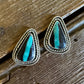 Pair of earrings with turquoise stones on a wooden surface
