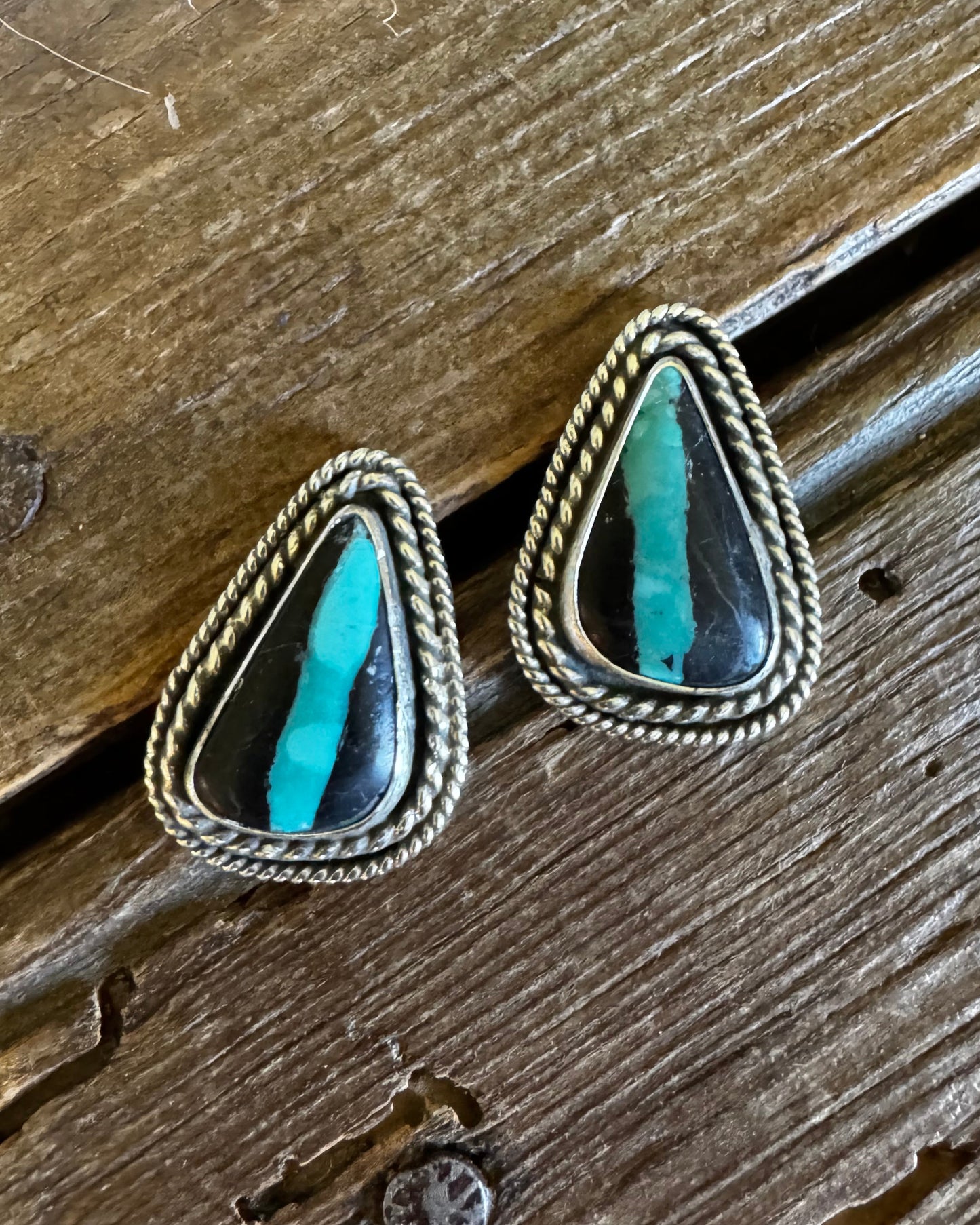 Pair of earrings with turquoise stones on a wooden surface