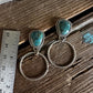 Pair of silver earrings with turquoise stones on a wooden surface with a ruler for scale.