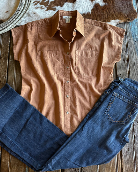 Brown shirt and blue jeans on a wooden surface with a cowhide rug.