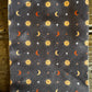 Socks with celestial pattern of suns, moons, and stars on a dark background