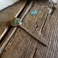 Turquoise stone pendant on a chain against a wooden background