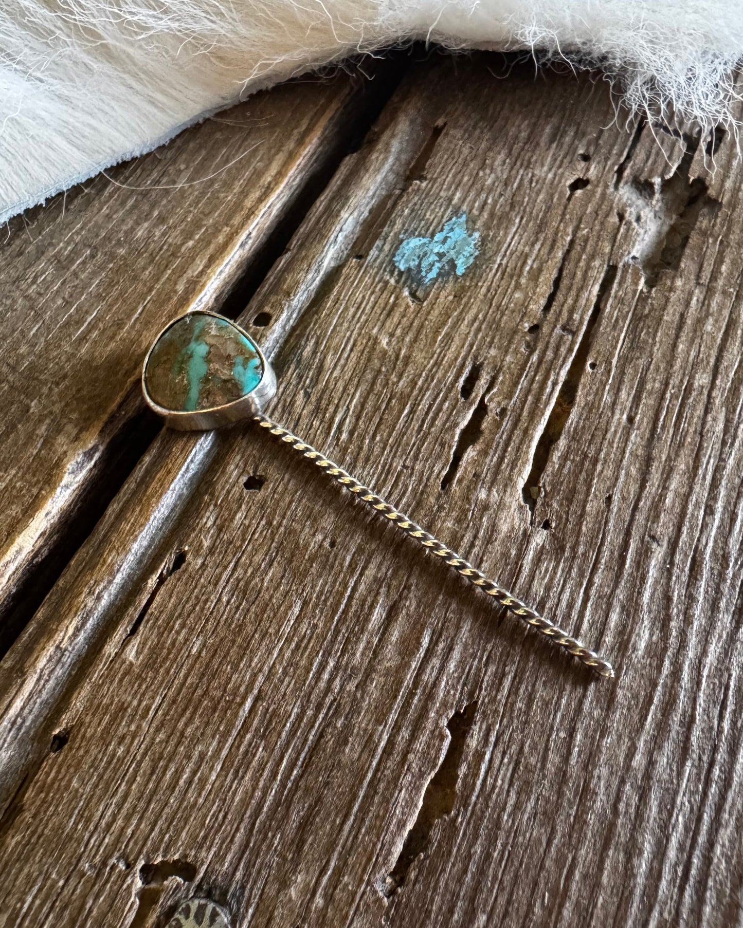 Turquoise stone pendant on a chain against a wooden background