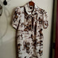 Shirt with horse pattern hanging on a hook against a white wall.