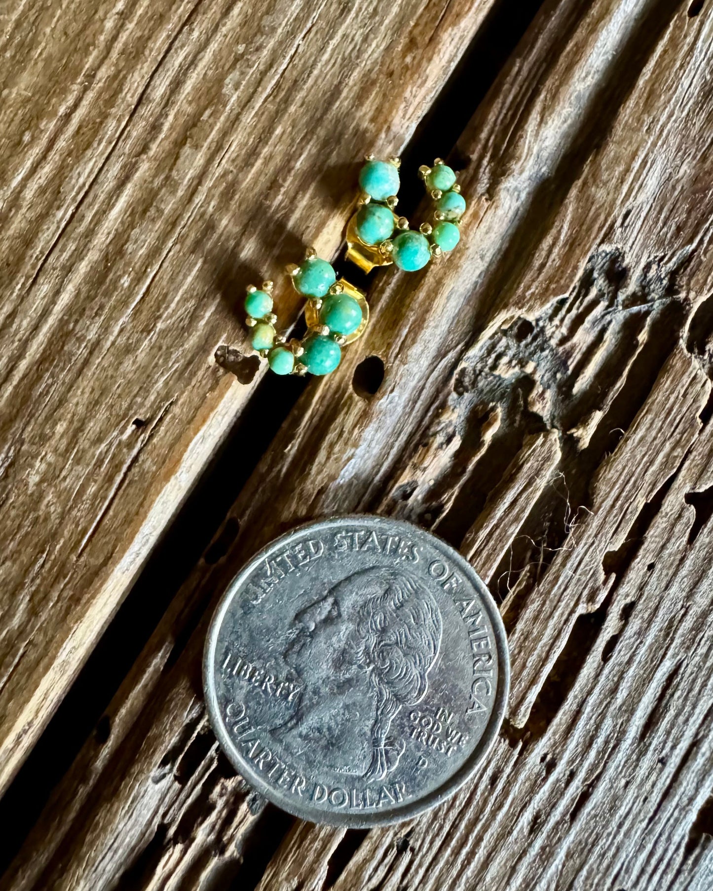 turquoise and gold horseshoe earrings on a rustic wooden background with a quarter