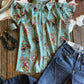Retro cowboy patterned shirt and jeans on a wooden surface with cowhide rug