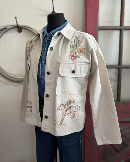White jacket with embroidery on a mannequin against a neutral background