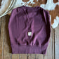 Purple sleeveless top on a wooden surface with a cowhide rug in the background