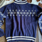 Navy blue sweater with white pattern on a wooden surface