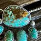 Turquoise stone pendant with silver setting on a wooden background