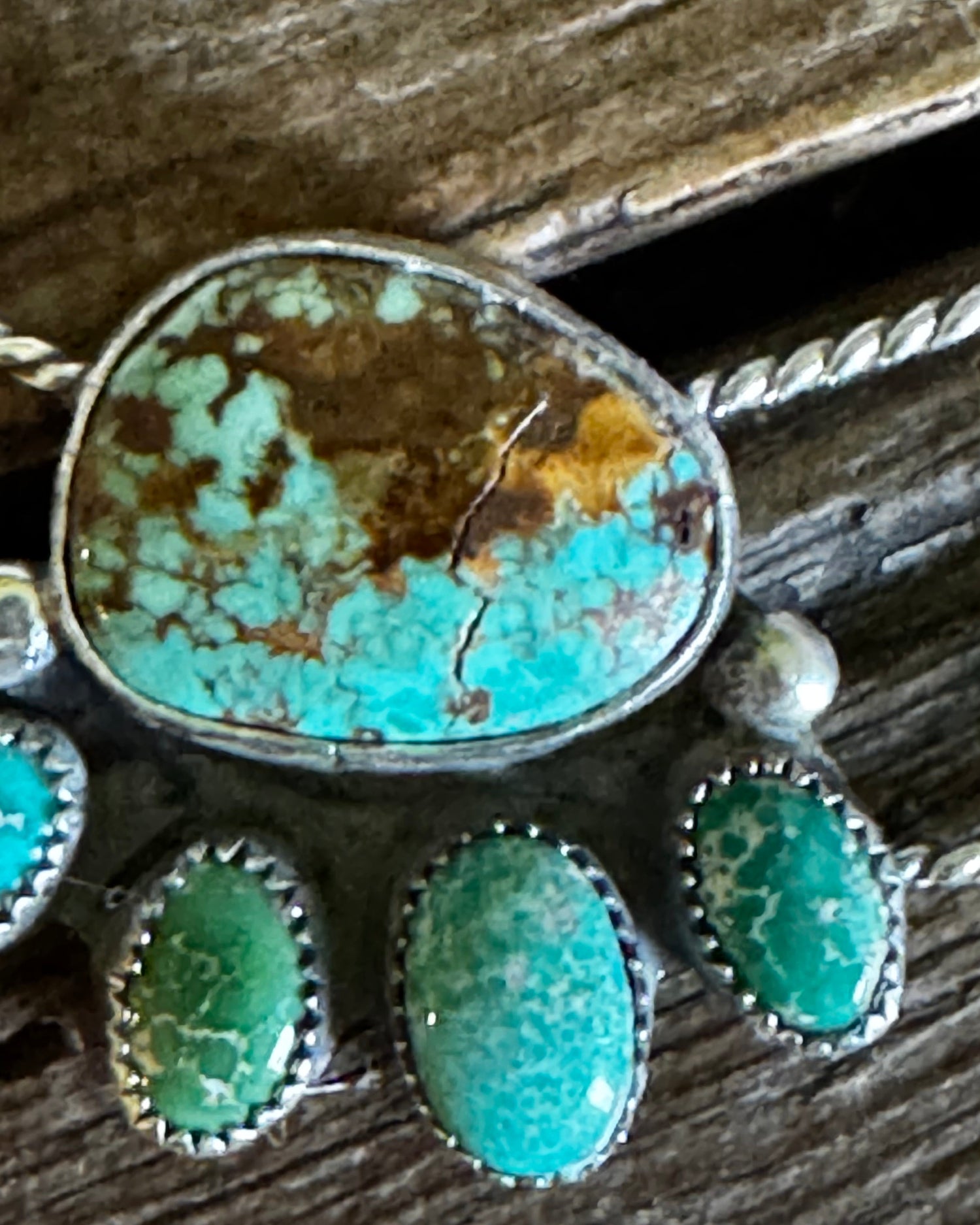 Turquoise stone pendant with silver setting on a wooden background